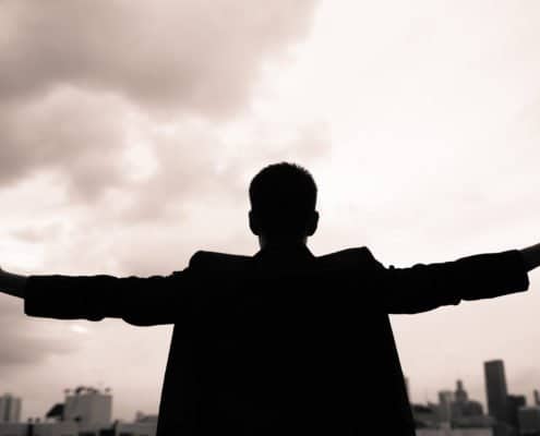 guy wearing suite holding hand up