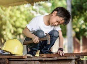 Kid working outdoors with wood