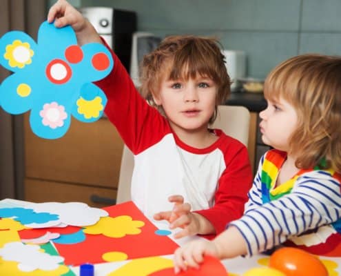 2 kids drawing on a kitchen table
