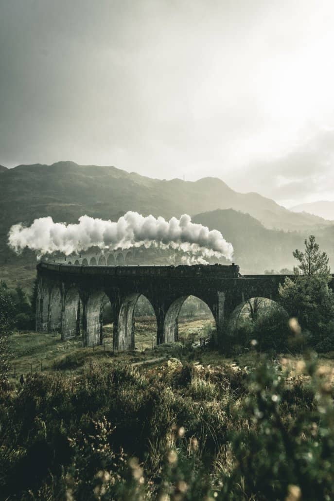 Train crossing a bridge with a steam coming out of it