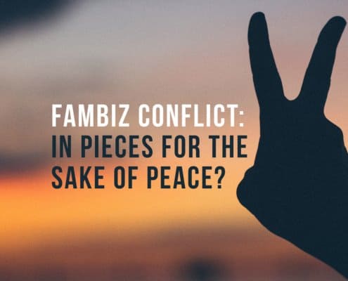 A hand making the sign of peace infront of a sunset