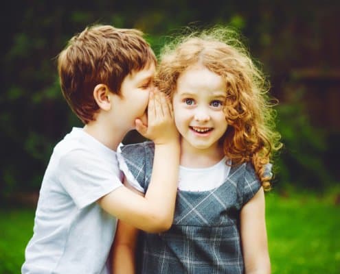 2 kids whispering to each other